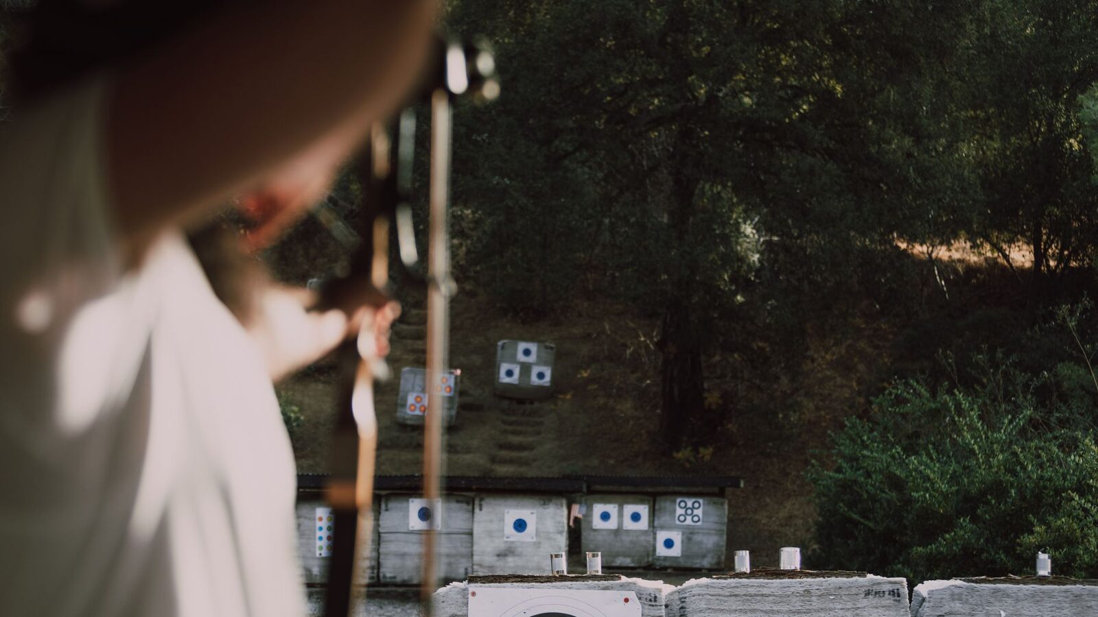 Archer concentré visant une cible colorée sur un parcours en sous-bois