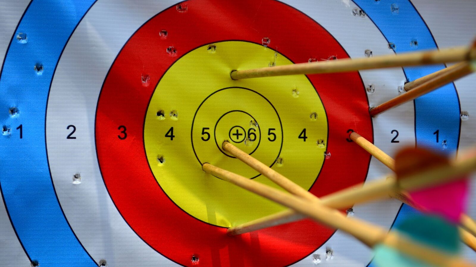Cible de tir à l'arc multicolore atteinte par plusieurs flèches